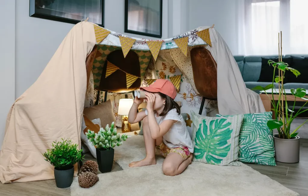 Kid in tipi tent using cardboard binoculars